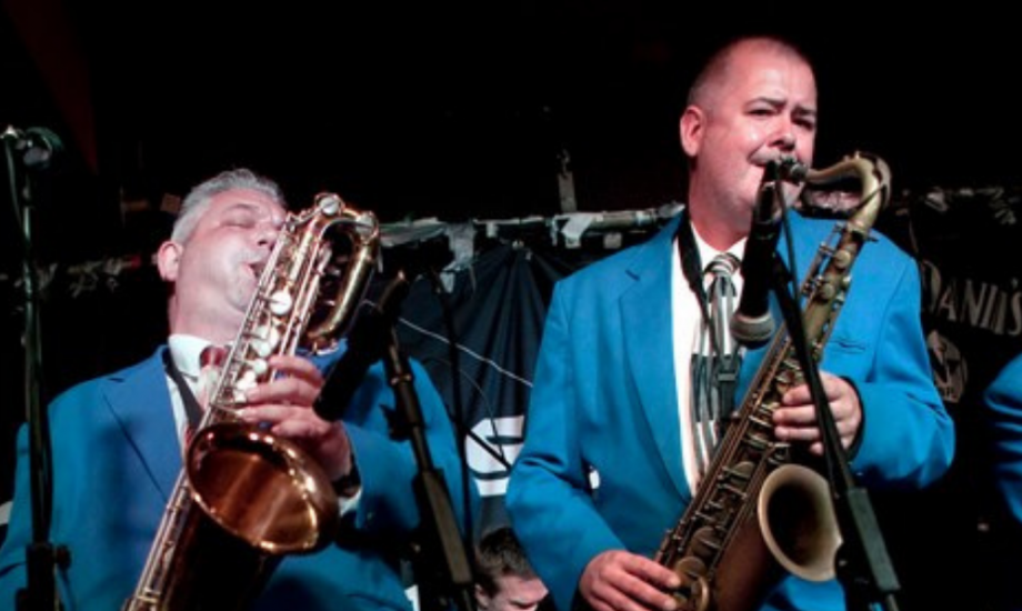 King Pleasure & The Biscuit Boys perform live on stage on royal blue suits.