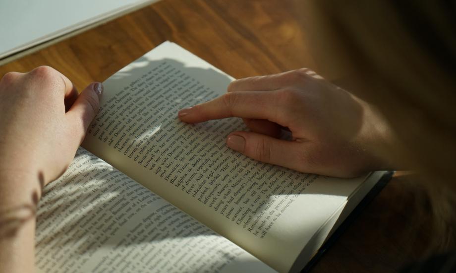 an image of a book with a hand tracing over the words